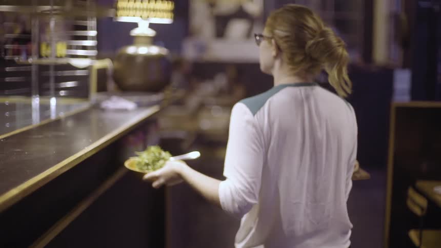 A waitress picking up an order and heading towards the dining room