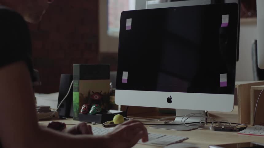A man is sitting at a desk working at a mac computer