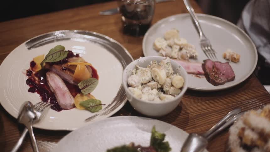 A glass of wine is picked up and sat down at a table filled with food