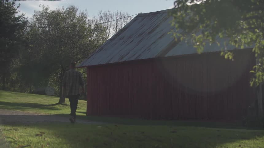 Man walks towards a barn on a sunny day