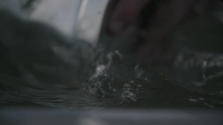 A tin can is being used to scoop up water
