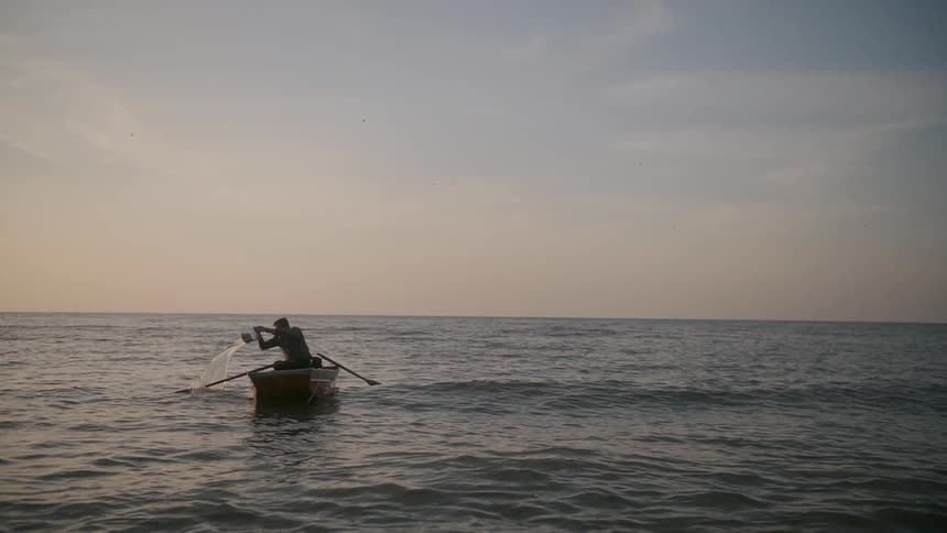 A man dumps a bucket off the side of his boat