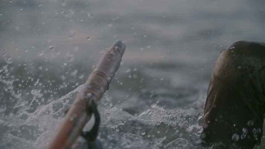 A person bails out a water filled boat with a bucket