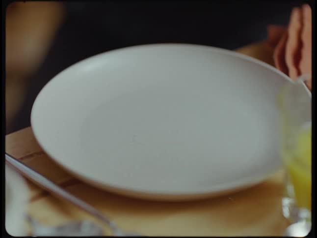 A person picks of a danish pastry from a plate and takes a bite