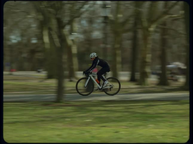 A woman riding a bicycle on a sidewalk through a park
