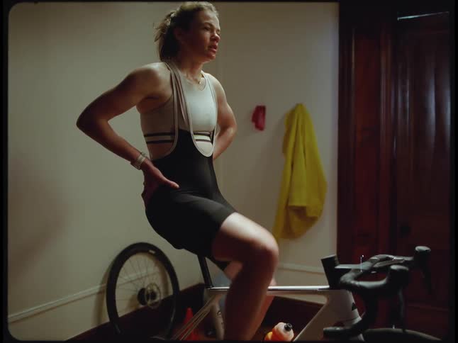 A woman rides an exercise bike at home