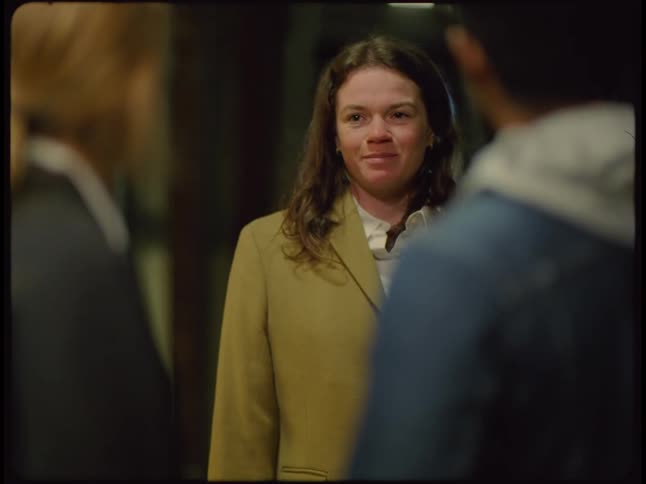 A woman wearing a yellow coat walking up to a man and woman talking says something to them and they turn and walk away and so does she