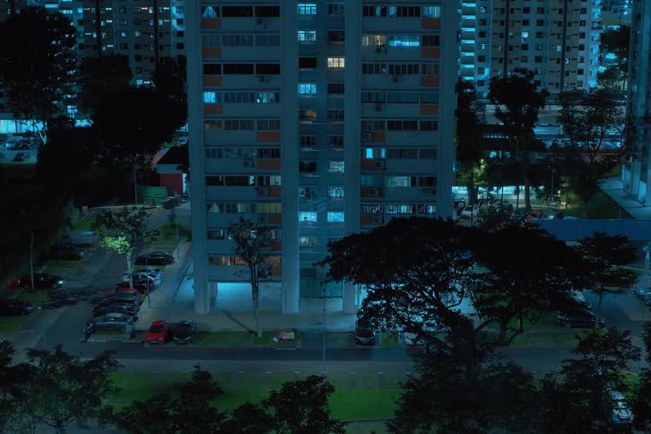Vehicles park at and drive past a downtown apartment building