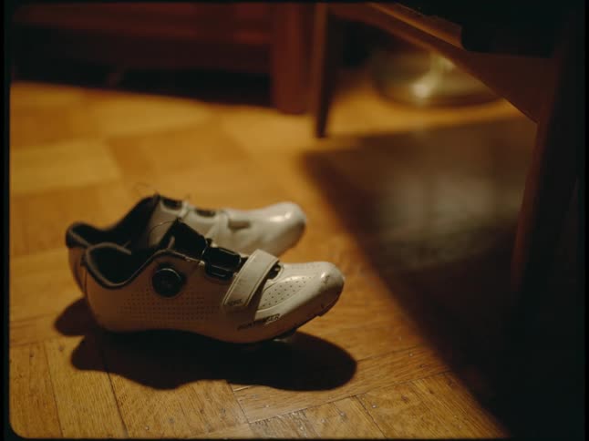 A pair of white sneakers with velcro on a wooden floor