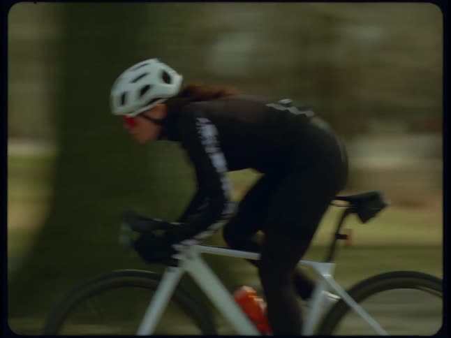 A woman rides her bike through the park