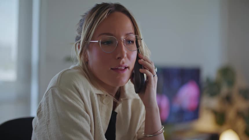 A woman holds her cell phone to her ear while having a conversation