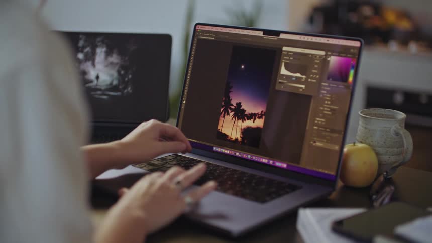A womans hands are shown using a trackpad on a laptop while editing the color of an image on the screen