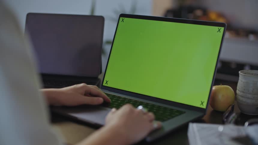 Woman with ring and white shirt works on laptop at desk