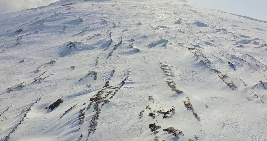 An aerial view of a snow covered mountain slope and peak