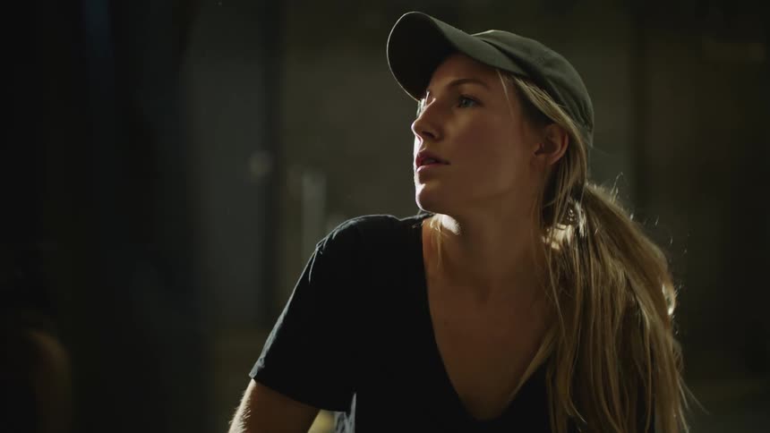 A woman is sitting down and wearing a hat