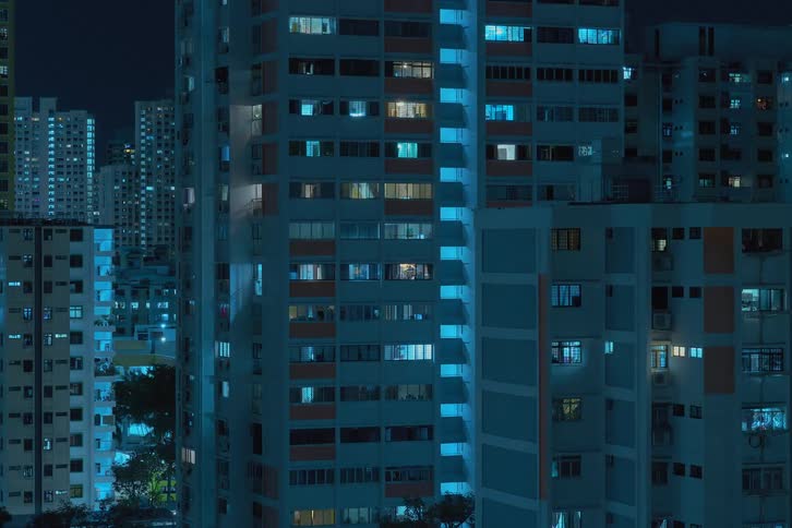 A time lapse of city buildings with windows and screens flashing on them