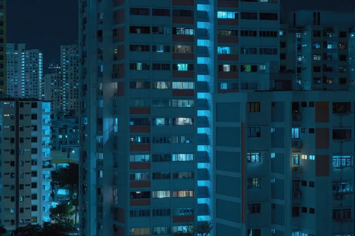 Tall white buildings in the city with windows on all levels and light flashing