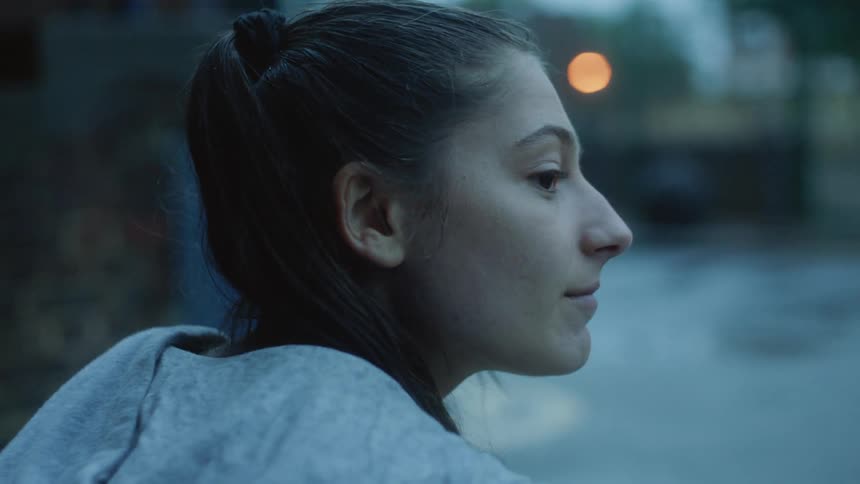 Woman with ponytail and gray jacket looks at man getting up and walking in the street