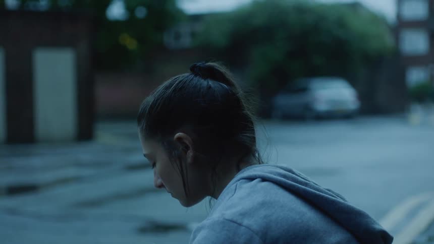 A sad woman sits next to a street