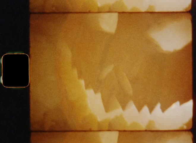 Super 8mm close up of a carved pumpkin with angry eyes and an evil smile surrounded by the smoke of burning candles glowing on a misty autumn night during a modern Halloween celebration providing a spooky experience