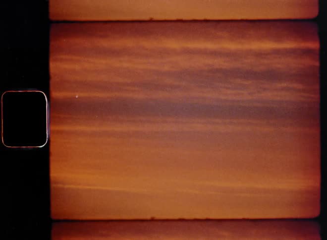 The picturesque sky is filled with orange clouds in vibrant colors and purple or lilac tones as the sun is setting and the afterglow creates an abstract but beautiful evening sky with glowing layers of clouds