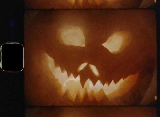 Scary and unsettling silhouette or shadow of an angry and evil Jack O'Lantern zooming out to reveal the complete face with a creepy grimace laughing in a crazy and mentally ill way causing fear and goose bumps with smoke and bright flickering flash lights
