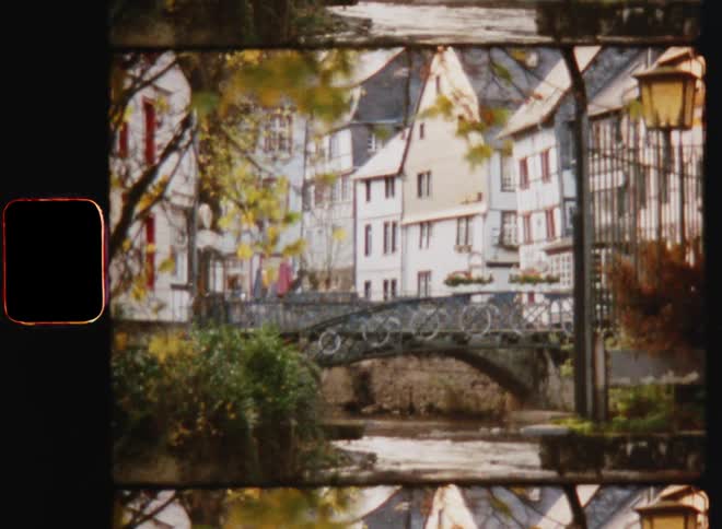 A footbridge crosses a stream in a neighborhood on an autumn day