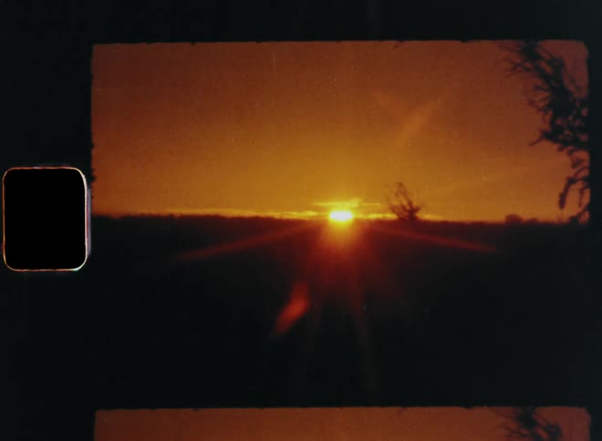 Panning Super 8 nature footage of the sun shining and rising at the horizon during a beautiful sunset as the new day starts or begins over a vast open field