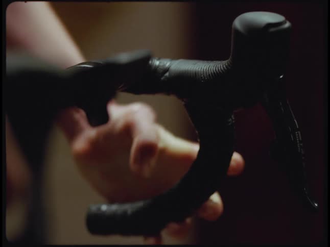 A woman gripping the handlebars of a stationary bike while working out