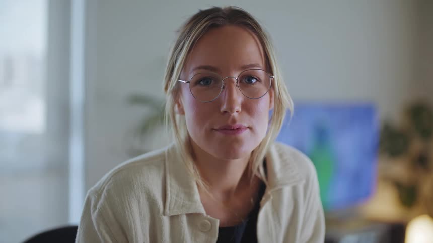 A portrait of a blonde woman wearing glasses indoors