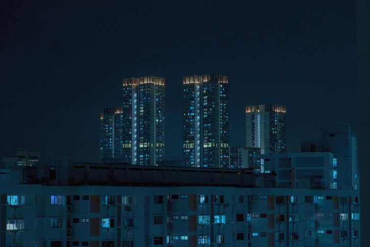 A time lapse of a city skyline with skyscrapers and a housing building showing lights and screen