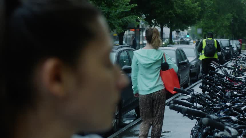 Woman with ponytail walking down the street looks over her shoulder at woman walking by