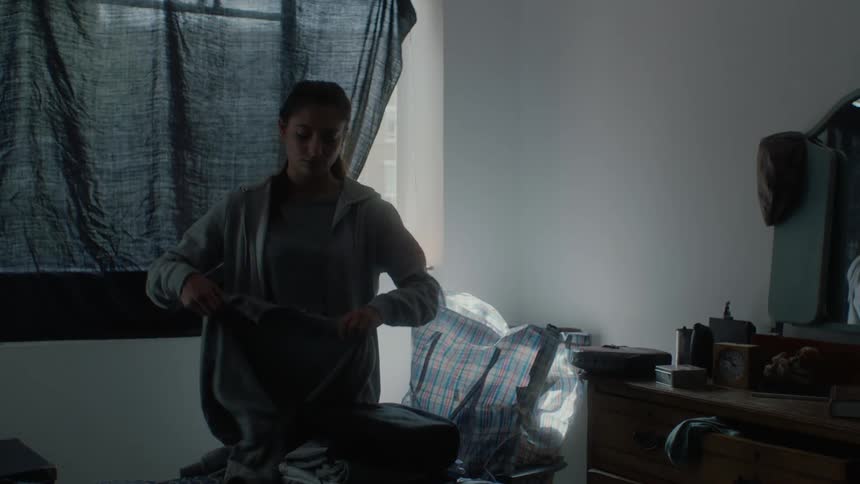 A female is folding laundry at her house