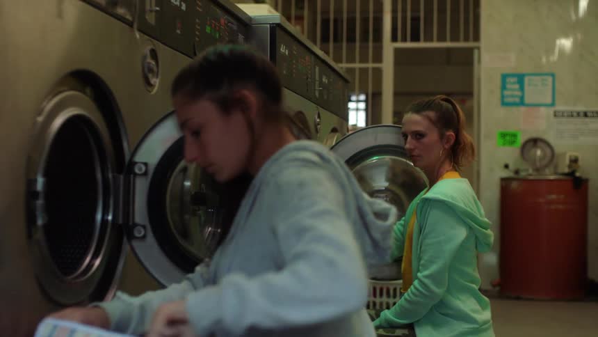 One woman at laundromat stares at another making the second woman uncomfortable