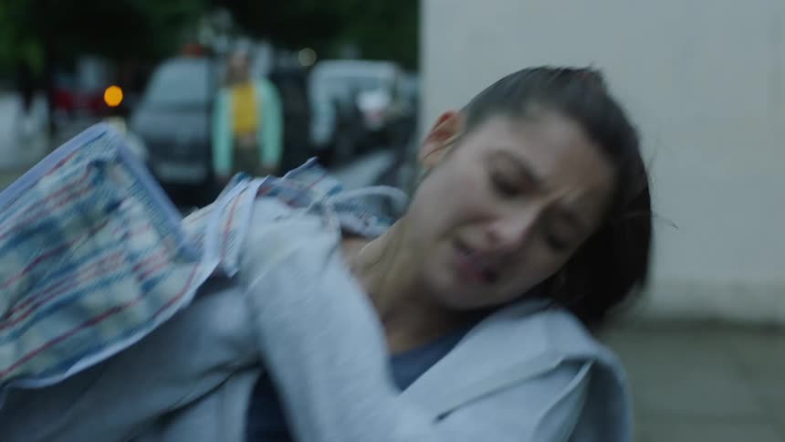 Woman with ponytail and gray jacket carries off a bag and gets out of laundry shop angrily