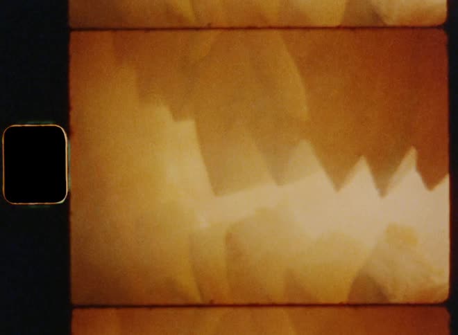 Vintage 8 mm close up of the angry and threatening mouth of a burning and smoking carved pumpkin jack o lantern with sharp teeth and a creepy smile causing fear in a retro scary movie