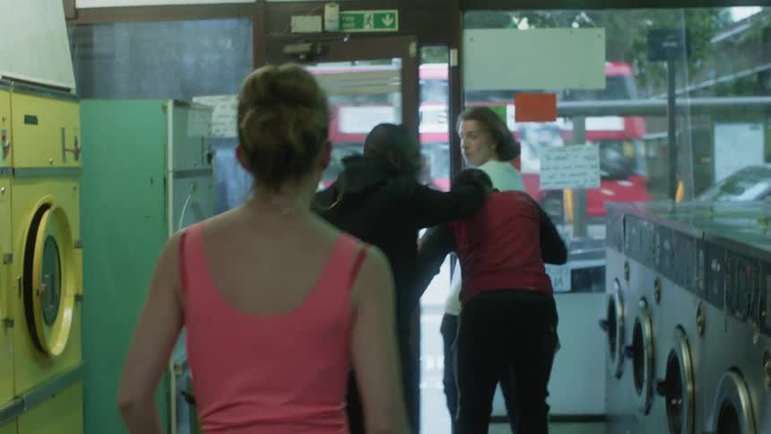 A young woman is fighting with these men at a laundromat