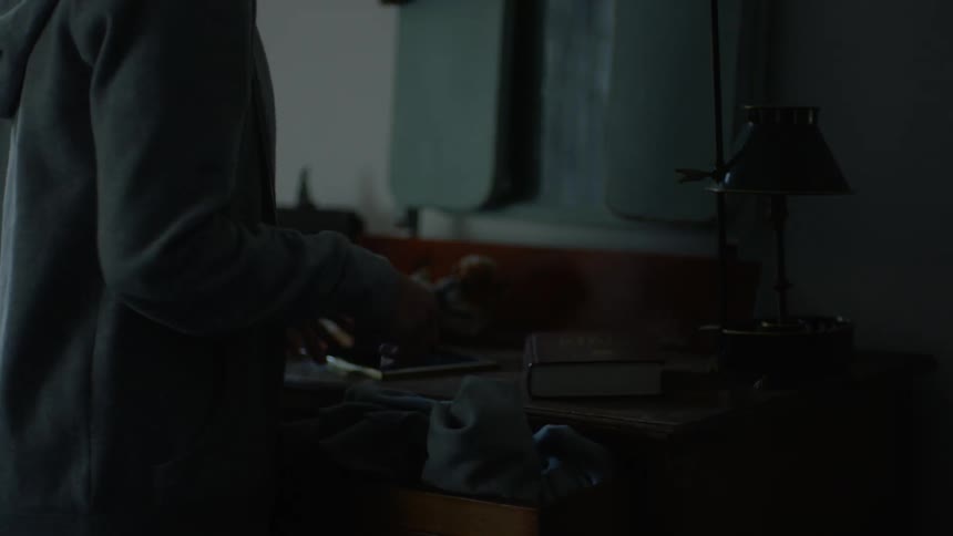 Woman with gray jacket folds the clothes and looks at photo in room