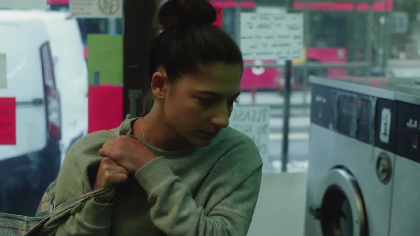 A woman walks into a laundromat during the day time