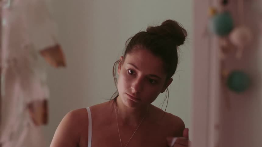 A woman undresses in the mirror