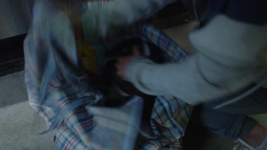A woman rushing into a laundromat getting clothes out of the machine putting them in a bag and rushing out the door while running into another woman