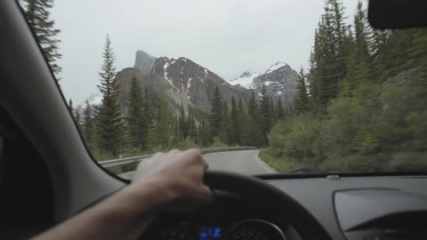 Driving along a mountain road with ice covered peaks in the distance