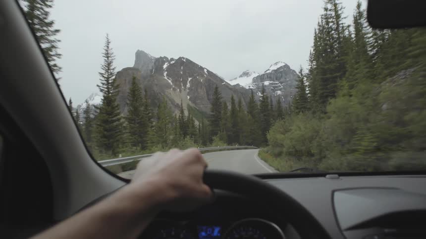 Driving along a mountain road with ice covered peaks in the distance