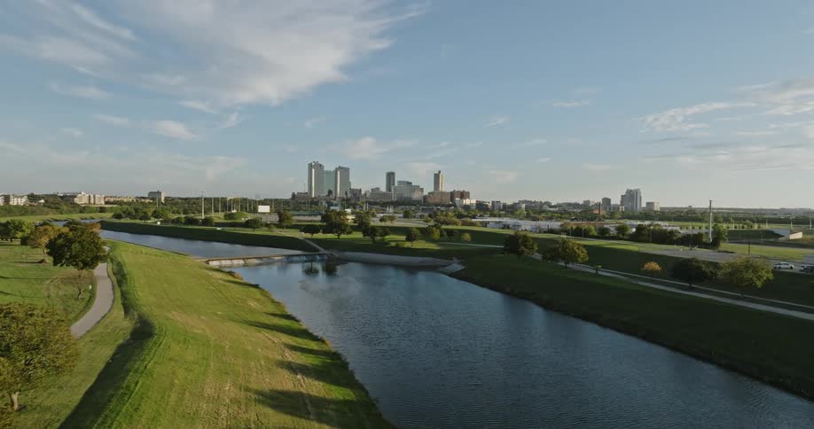 Aerial view of river with green bank and city skyline