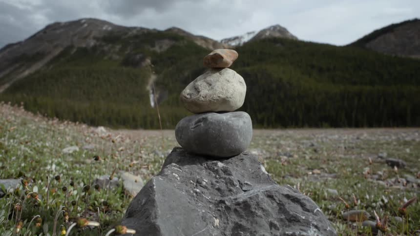 Rocks sit on top of each other in a valley at the base of mountains