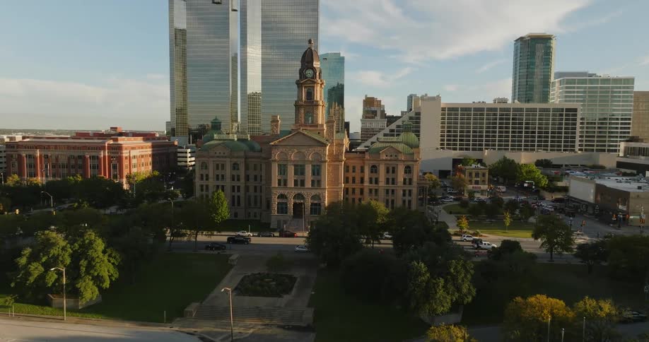 Traffic moves on the streets near a building with a clock tower with amazing architecture as city buildings and towers stand tall on the city skyline