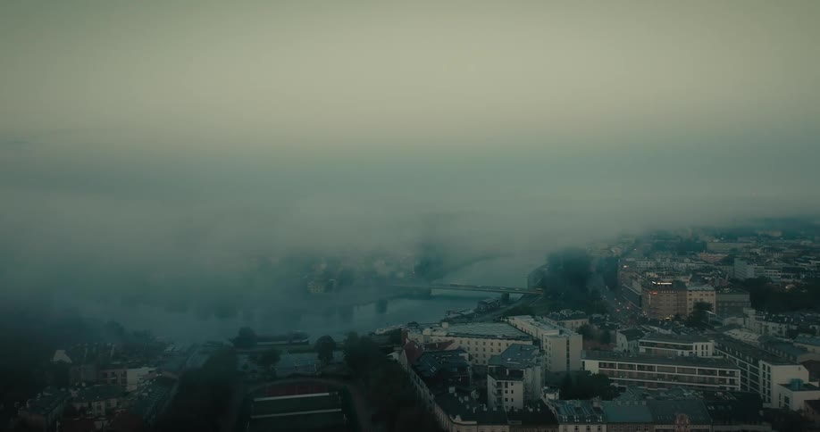 Fog densely covers riverbank across bridge from apartment buildings