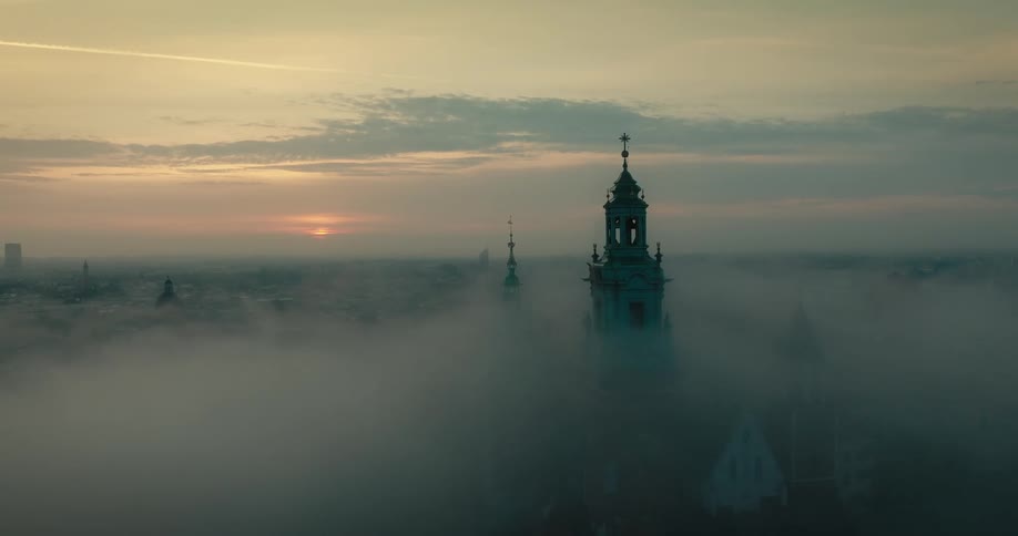 Fog settling over a city and a church tower at dawn