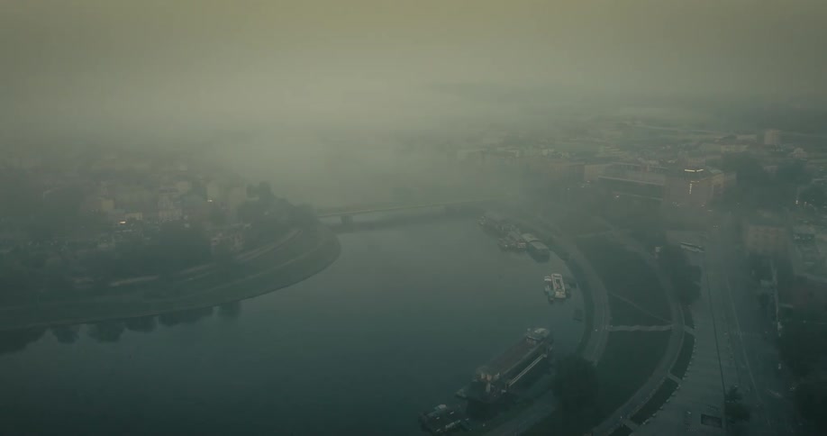 An aerial view of a city with a river on a foggy morning