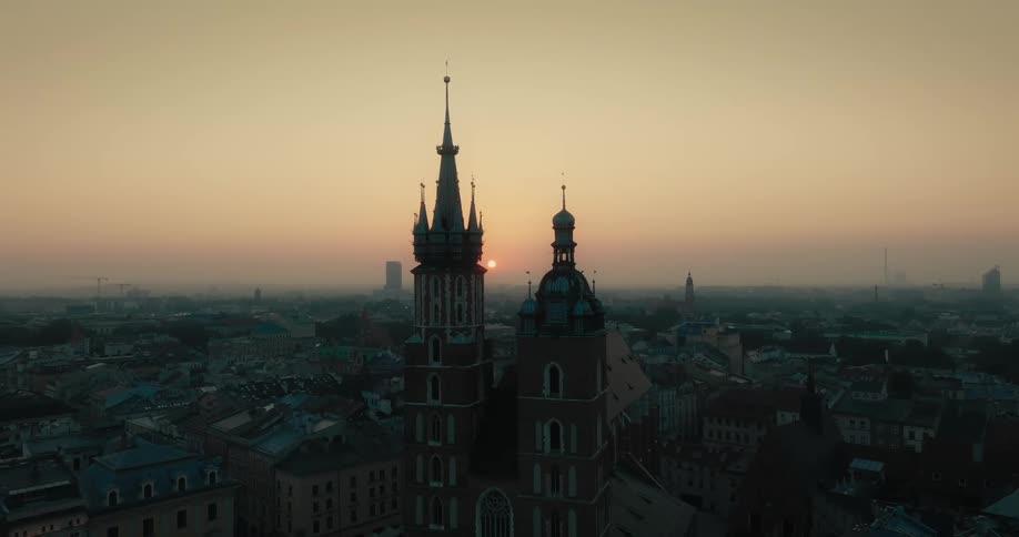 Aerial orbital view of the sunset sun behind the towers of a gothic cathedral